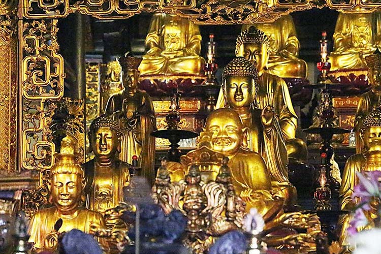 De nombreuses statues de Bouddha sont en bronze étincelant à la pagode Tran Quóc