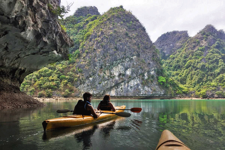 Touriste en kayak devant les falaises de la baie d’Halong